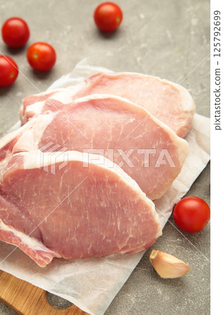 Sliced raw pork meat on cutting board on grey concrete background. Vertical photo 125792699