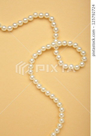 Elegant pearl necklace on beige background, top view. Space for text Elegant pearl necklace on beige background, top view. Space for text 125792724