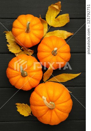 Autumn composition. Orange pumpkin with autumn leaves on black background. Thanksgiving day. Vertical photo Autumn composition. Orange pumpkin with autumn leaves on black background. Thanksgiving day. Vertical photo 125792751