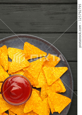 Nachos and ketchup on plate on black background. Mexican dish. Top view Nachos and ketchup on plate on black background. Mexican dish. Top view 125792795