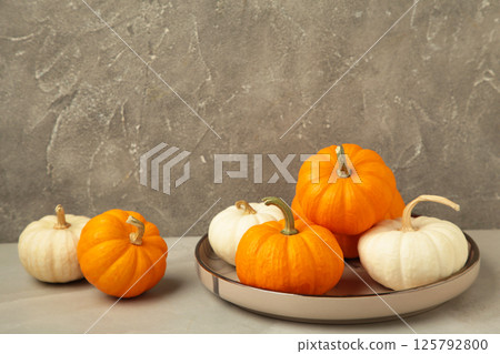 Autumn composition. Fresh orange and white pumpkin on plate on grey background. Top view 125792800