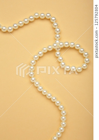 Elegant pearl necklace on beige background, top view. Space for text 125792804
