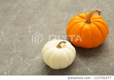 Mini orange and white pumpkins on grey concrete background. Space for text 125792877