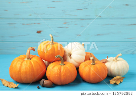 Festive autumn decor from pumpkins and leaves on blue wooden background. Concept of Thanksgiving day or Halloween. Festive autumn decor from pumpkins and leaves on blue wooden background. Concept of Thanksgiving day or Halloween. 125792892