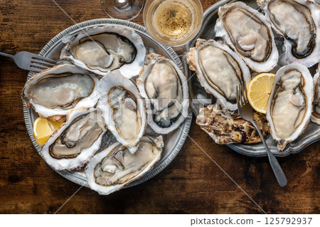 Fresh raw oysters on ice, overhead flat lay shot of two platters with champagne Fresh raw oysters on ice, overhead flat lay shot of two platters with champagne 125792937