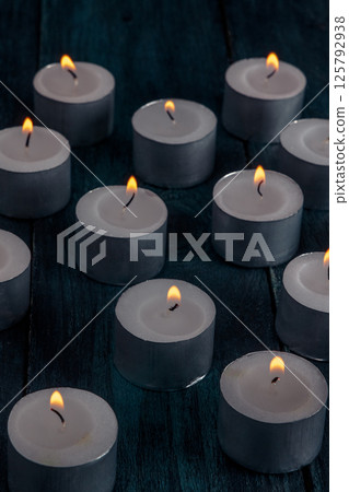 Tea light candles on a dark background, many lights in the dark Tea light candles on a dark background, many lights in the dark 125792938