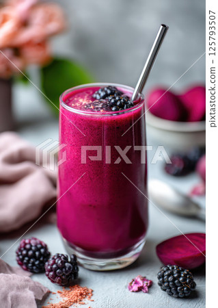 Vibrant blackberry and beet smoothie in a glass with metal straw and fresh berries on gray background. 125793507
