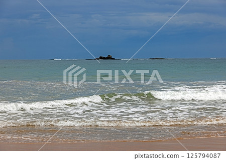 Tranquil tropical sea with small waves breaking on a sandy shore and no people visible 125794087