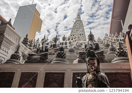 Many Buddha statues in a Colombo temple with stone pagoda in the background, no people visible 125794194
