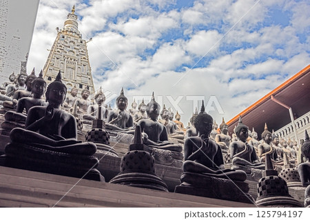 Many Buddha statues in a Colombo temple with stone pagoda in the background, no people visible Many Buddha statues in a Colombo temple with stone pagoda in the background, no people visible 125794197