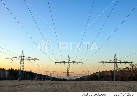 High voltage power lines over a field at sunset High voltage power lines over a field at sunset 125794296