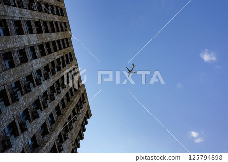 A regular plane in the sky comes in to land over a modern residential complex. 125794898