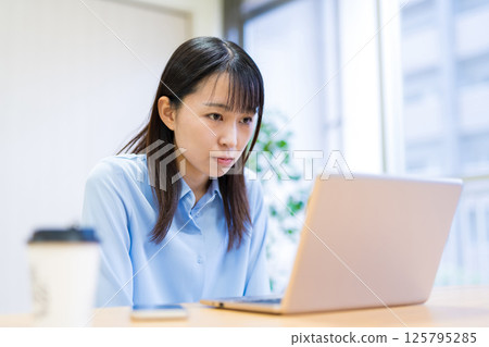 A young woman working remotely in the living room, looking at the screen seriously 125795285