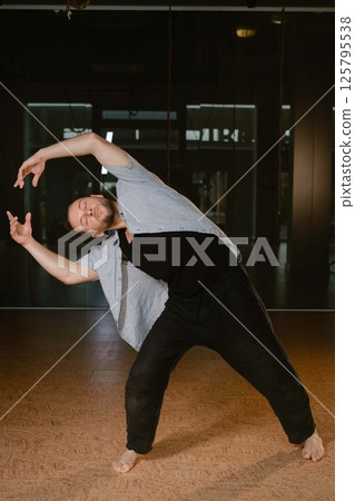 A man performs erratic movements during a yoga class at a fitness gym 125795538