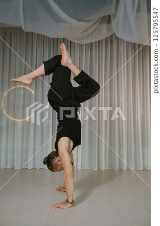 A man stands upside down on his hands in the gym 125795547