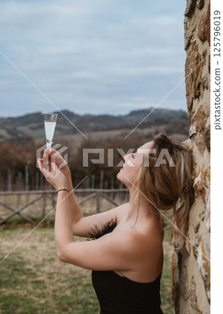 Woman Toasts with Champagne Glass in Scenic Vineyard Woman Toasts with Champagne Glass in Scenic Vineyard 125796019