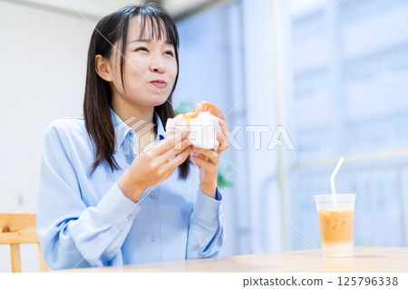 A woman eating a hamburger in the living room 125796338
