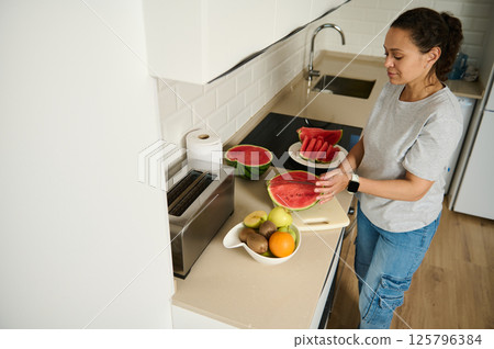 Woman Preparing Fresh Watermelon in a Modern Home Kitchen 125796384