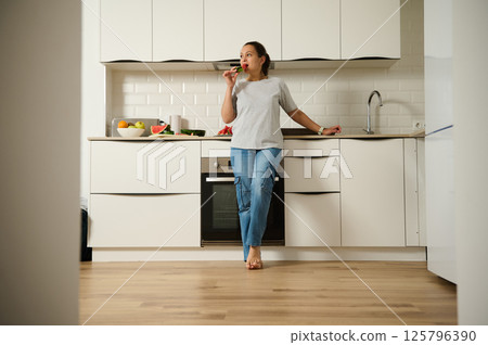 Woman Relaxing in Modern Kitchen With Healthy Fruits on Countertop 125796390