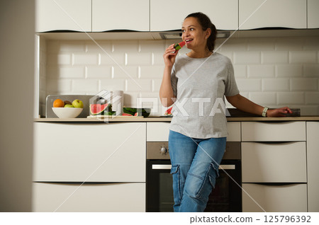 Woman Enjoying Healthy Snack in Modern Kitchen Interior 125796392
