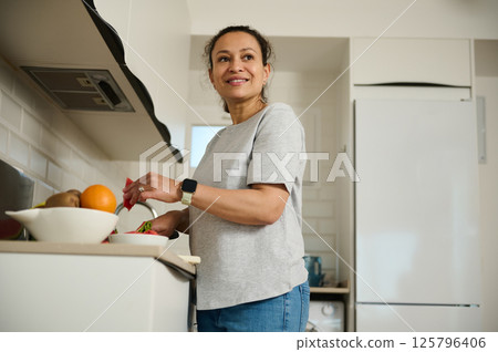 Smiling Woman in Kitchen Preparing Healthy Meals with Fresh Ingredients 125796406