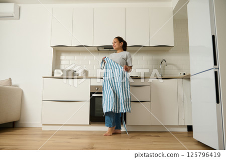 Woman Holding Apron in Modern Kitchen Interior for Domestic Lifestyle 125796419