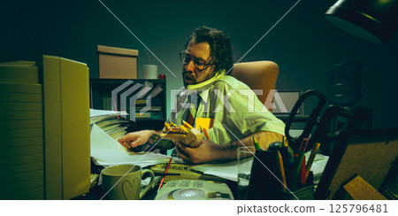 Overwhelmed man holding sandwich buried in paperwork, talks on phone while checking documents, portraying corporate burnout and multitasking Overwhelmed man holding sandwich buried in paperwork, talks on phone while checking documents, portraying corporate burnout and multitasking 125796481