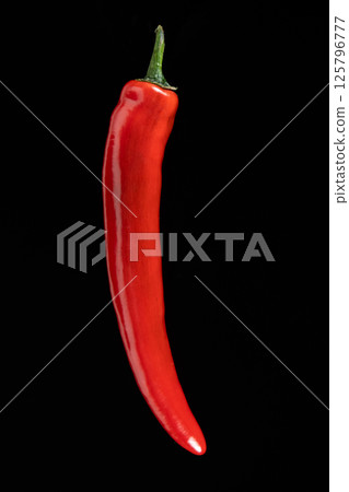 One hot red chili pepper on a black background close-up. 125796777