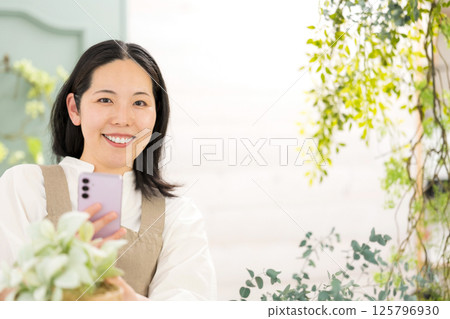 Middle-aged woman photographing plants indoors | Flower shop gardening shop classroom image | Well-being girl | Well-being 125796930