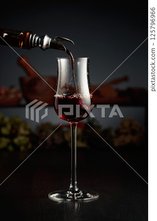 Brown herbal liquor or rum is poured from a vintage bottle. Brown herbal liquor or rum is poured from a vintage bottle. 125796966