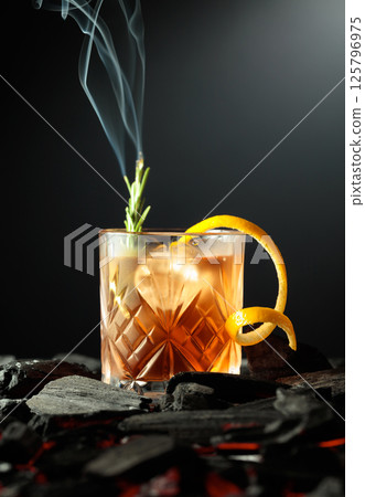 Old-fashioned cocktail with a burning twig of rosemary. Old-fashioned cocktail with a burning twig of rosemary. 125796975