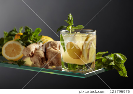 Ginger cocktail with lemon and mint in a frozen glass on a black background. 125796976