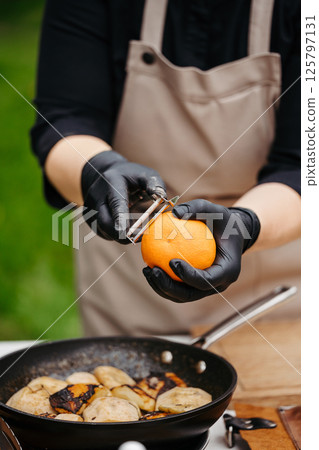 Chef cooking apples with brown sugar, orange and butter in pan. 125797131