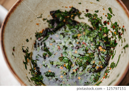 High angle view of fresh chimichurri sauce with herbs and olive oil. High angle view of fresh chimichurri sauce with herbs and olive oil. 125797151