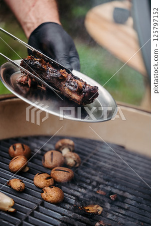 Grilling beef ribs and mushrooms on barbecue grill. 125797152