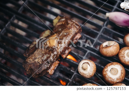 Grilling beef ribs and mushrooms on barbecue grill. 125797153