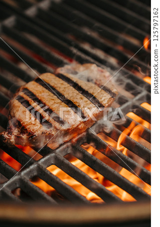 Grilling New York Strip steak over open flame on barbecue grill. Grilling New York Strip steak over open flame on barbecue grill. 125797162