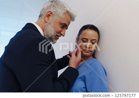 Hospital manager harassing attractive nurse in healthcare setting. Hospital manager harassing attractive nurse in healthcare setting. 125797177