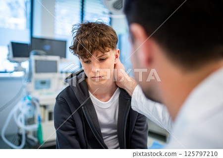 Depressed teenage patient sitting on hospital bed, talking with caring doctor. 125797210