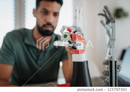 Young engineer building and programming a robotic arm at home. 125797303