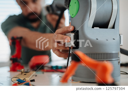 Close up of engineer's hands building and programming a robotic arm at home. Close up of engineer's hands building and programming a robotic arm at home. 125797304