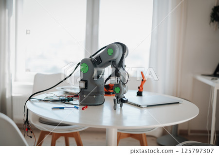Robotic arm prototype on a table in a home workspace. Robotic arm prototype on a table in a home workspace. 125797307