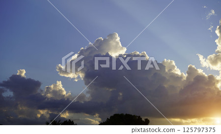 Golden sunset sky background, golden clouds, evening with the sun setting. Golden sunset sky background, golden clouds, evening with the sun setting. 125797375
