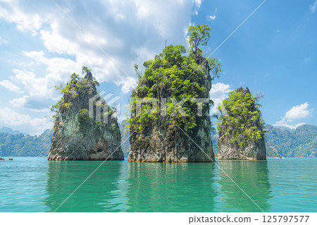 A panorama of famous natural places in Thailand - Three rocks, like three brothers, in the middle of turquoise water on the emerald Cheo Lan Lake in Khao Sok Park. The business card of tourism and A panorama of famous natural places in Thailand - Three rocks, like three brothers, in the middle of turquoise water on the emerald Cheo Lan Lake in Khao Sok Park. The business card of tourism and 125797577