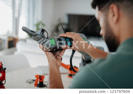 Close up of engineer's hands building and programming a robotic arm at home. 125797609