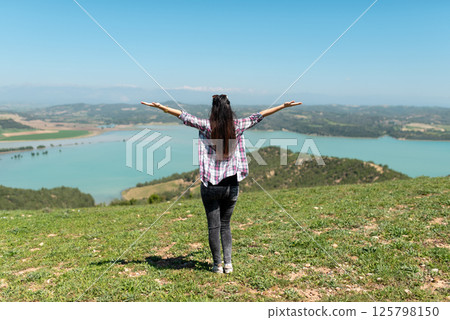 Happy woman rear view shot with her arms raised up. Happy woman rear view shot with her arms raised up. 125798150