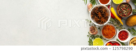 A mix of dried herbs and spices laid out on a gray background, highlighting natural flavors and culinary essentials, top view and copy space, banner 125798290