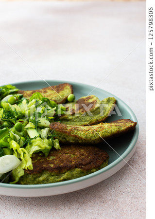 Zucchini and broccoli pancakes served with a mixed salad of cucumbers, young peas, and radishes Zucchini and broccoli pancakes served with a mixed salad of cucumbers, young peas, and radishes 125798306