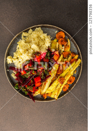 Enjoy a hearty breakfast or lunch with millet, baked zucchini, and carrots, paired with a fresh salad of seasonal vegetables and herbs, for a delicious vegetarian meal 125798356
