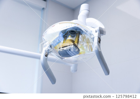 Modern Dental Equipment: A Close-Up of a Sleek, Advanced Dental Light Fixture Hanging in a State-of-the-Art Dental Office Setting Modern Dental Equipment: A Close-Up of a Sleek, Advanced Dental Light Fixture Hanging in a State-of-the-Art Dental Office Setting 125798412